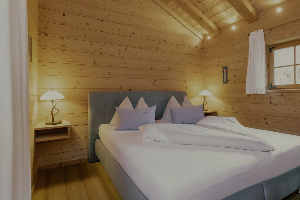 Schlafzimmer in einem der Chalets im Naturresort PURADIES mit gemütlichem Doppelbett und Holzwand/-decke