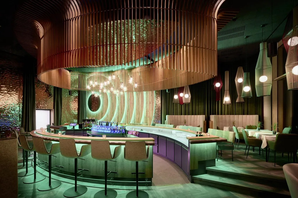 Hotelbar im Wellnesshotel Riedlberg mit elyptischem Holzdeckenelement und grüner Beleuchtung