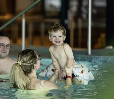 Familie mit kleinem Kind spielt gemeinsam im Indoorpool des Familotel Elldus Resort