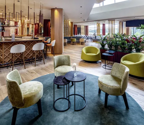 Stilvolle Bar im Falkensteiner Family Hotel Montafon mit Holztheke, modernen Sitzgelegenheiten und Pflanzen