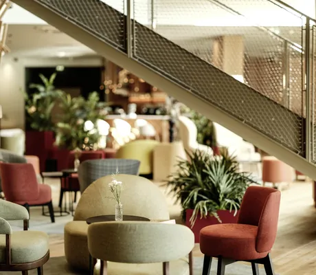 Nahaufnahme eines Sitzbereichs in der modernen Lobby des Falkensteiner Family Hotels Montafon mit Pflanzen und stilvollem Design