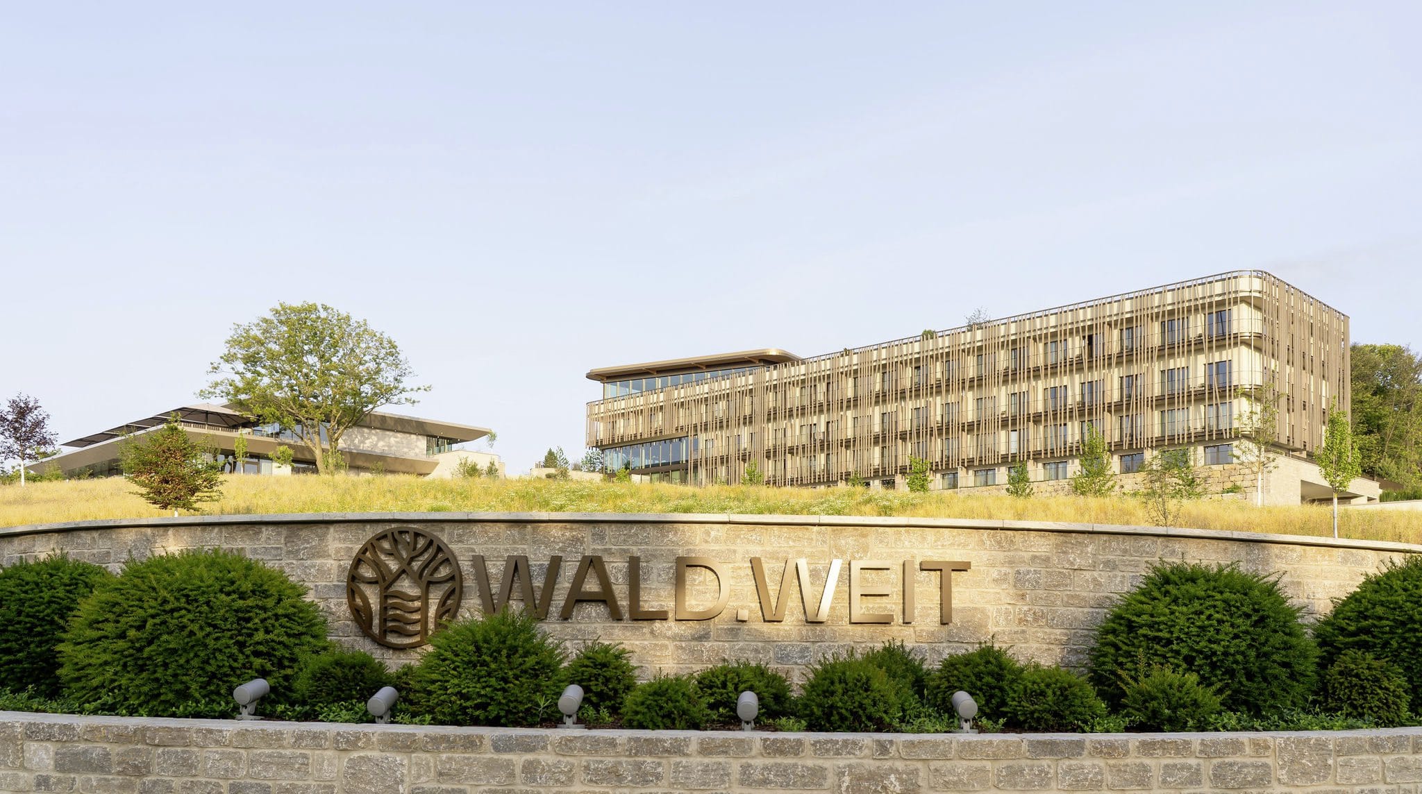 Außenaufnahme des WALD.WEIT mit Außenmauer mit Hotelnamen
