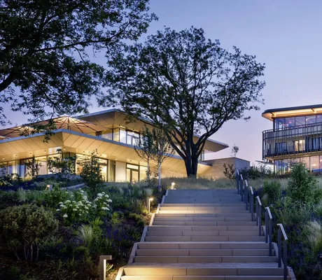 beleuchtete Außentreppe zu zwei Gebäuden des WALD.WEIT im Abendlicht