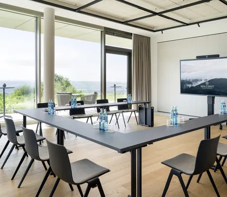 in U-Form bestuhlter Tagungsraum im WALD.WEIT mit Monitor und großem Panoramafenster