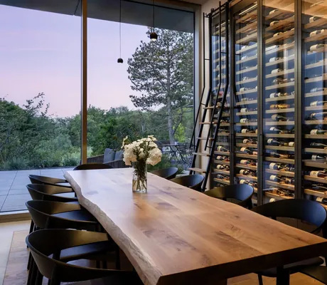 langer Holztisch mit acht Stühlen im WALD.WEIT neben Weinschrank