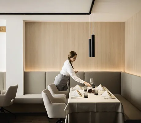 Eine Mitarbeiterin deckt den Tisch im Restaurant des MyParadies Sulden ein.