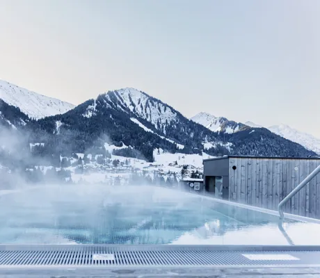 Sky-Infinitypool im Morgengrauen vor schneebedeckten Berghängen des Hotels Sonnenburg.