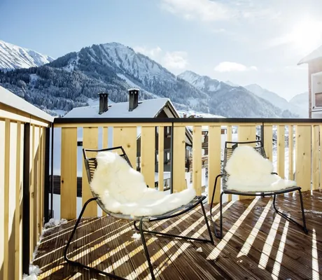 Terrasse im Hotel Sonnenburg in Riezlern mit Stühlen, Lammfell und Bergblick.