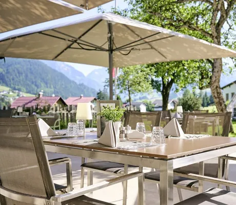 Eingedeckter Tisch auf der Outdoor Veranda bei strahlender Sonne im Hotel Sonnenburg.