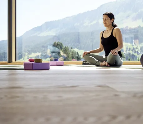Eine Frau meditiert im Fitnessraum des Hotel Sonnenburg in Riezlern.