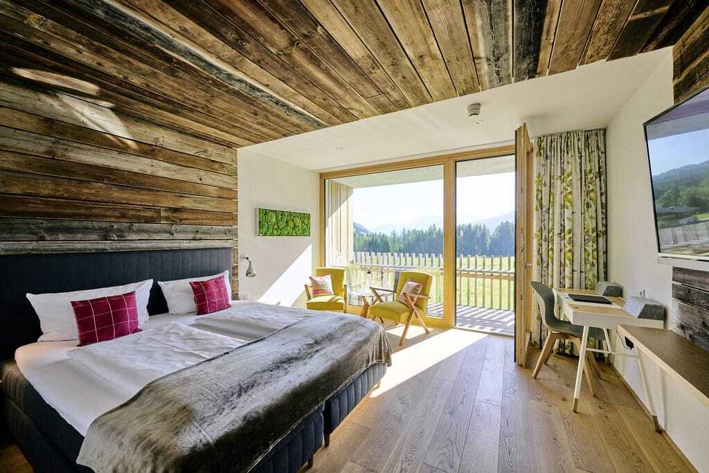Blick in ein gemütliches Doppelzimmer mit Naturmaterialien und Veranda im Hotel Sonnenburg.