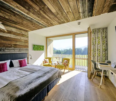 Blick in ein gemütliches Doppelzimmer mit Naturmaterialien und Veranda im Hotel Sonnenburg.