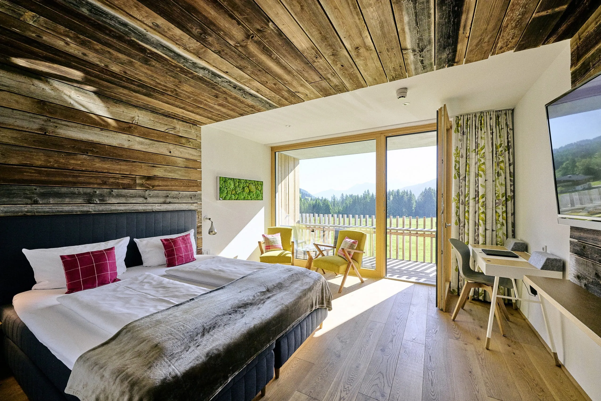 Blick in ein gemütliches Doppelzimmer mit Naturmaterialien und Veranda im Hotel Sonnenburg.