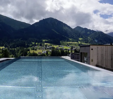 Blick vom Sky-Infinitypool des Hotel Sonnenburg auf die umliegenden grünen Hügel und Wälder.