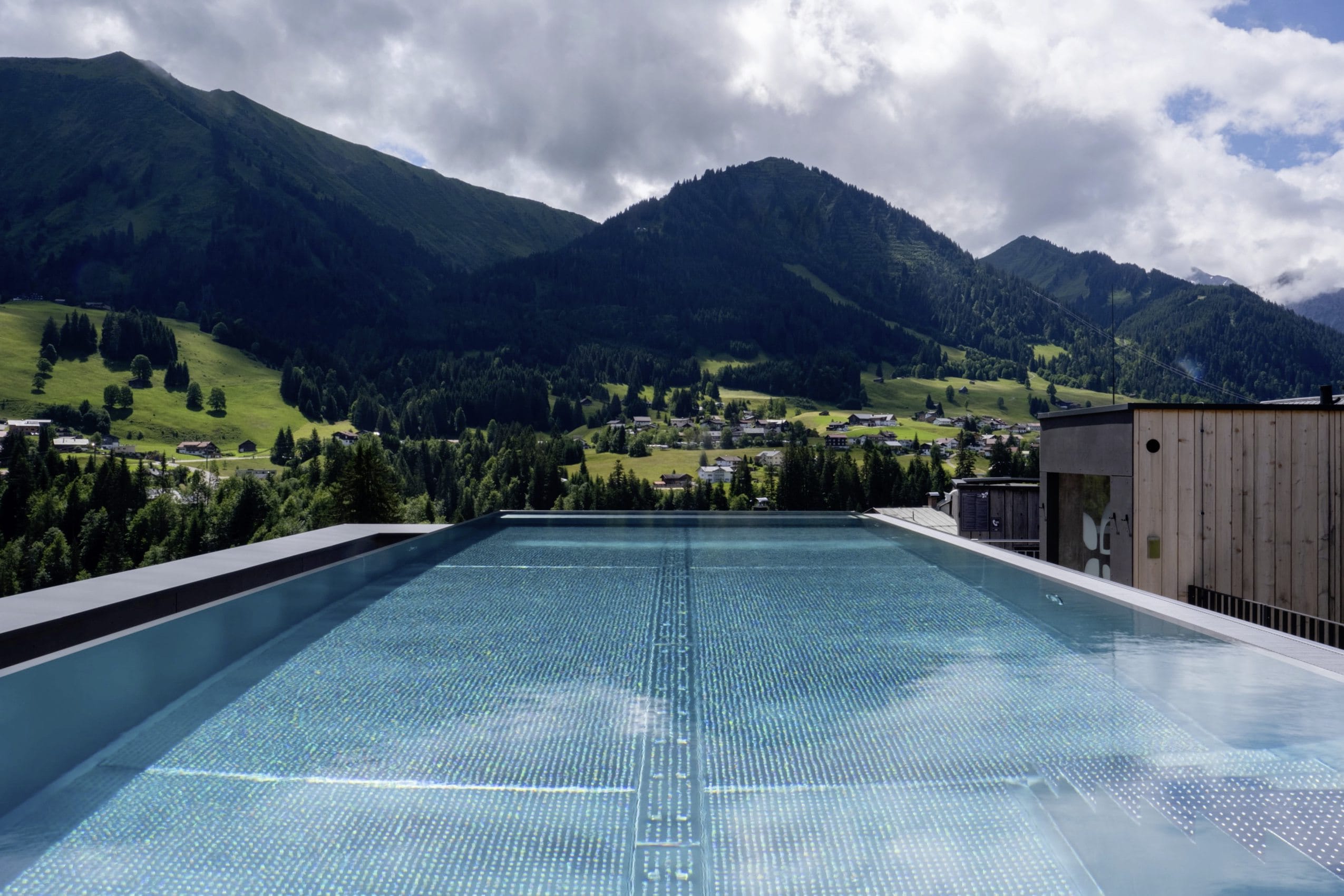 Blick vom Sky-Infinitypool des Hotel Sonnenburg auf die umliegenden grünen Hügel und Wälder.