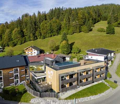 Vogelperspektive auf das Hotel Sonnenburg in Rietzlern mit dahinterliegenden grünen Hügeln und Bäumen.