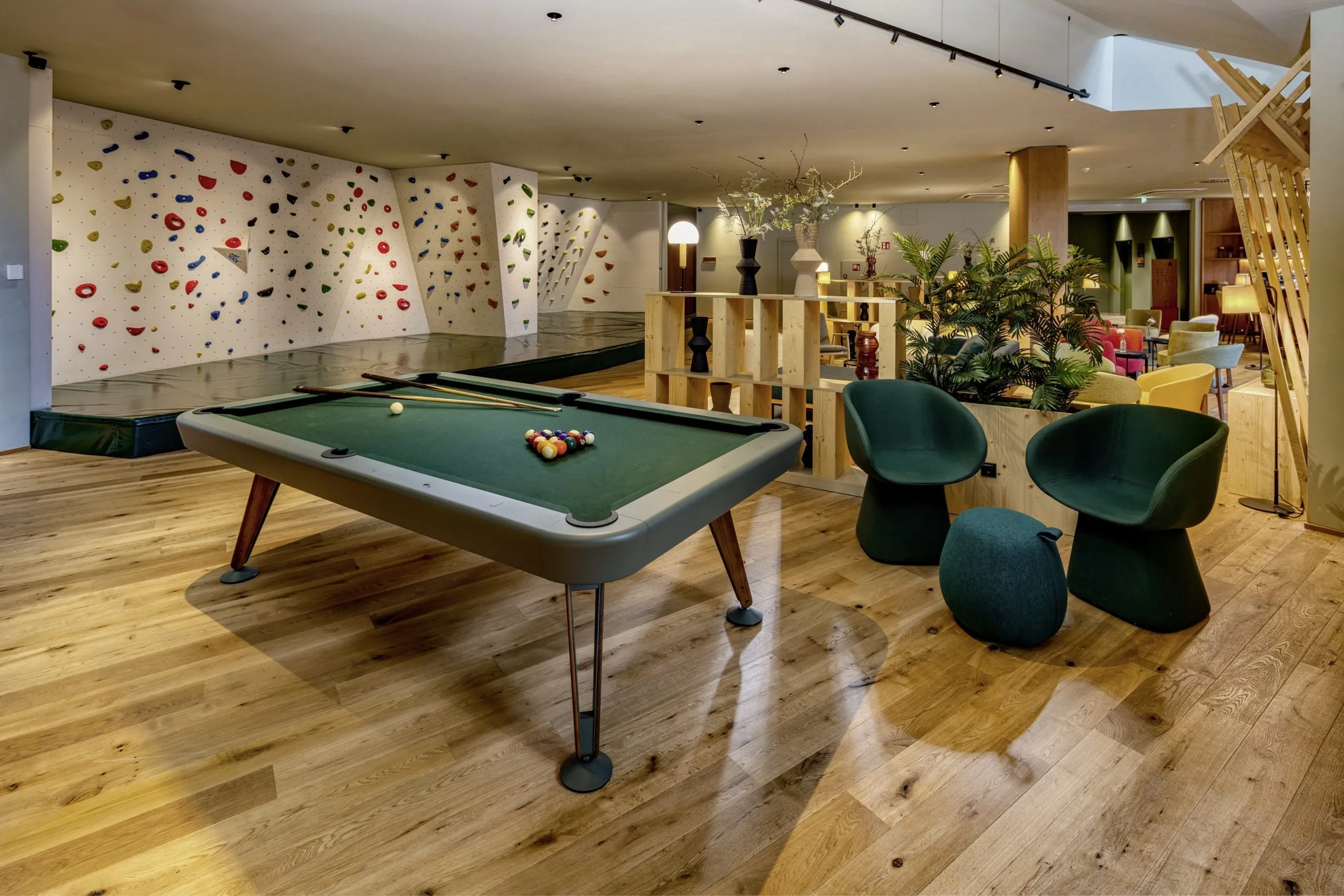 Billardtisch und Indoor-Kletterwand in der modernen Lobby des Falkensteiner Family Hotels Montafon mit gemütlichen Sitzbereichen