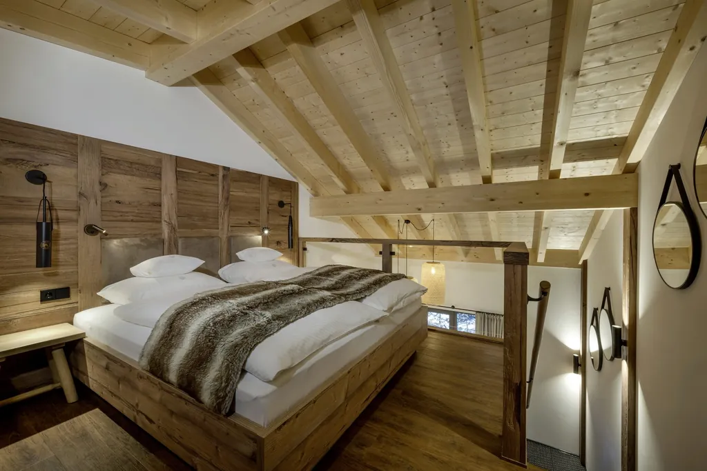 Gemütliches Schlafzimmer in einem der HofgutLofts mit Holzbalken-Decke und rustikalem Doppelbett aus Holz im Sonnenalp Resort