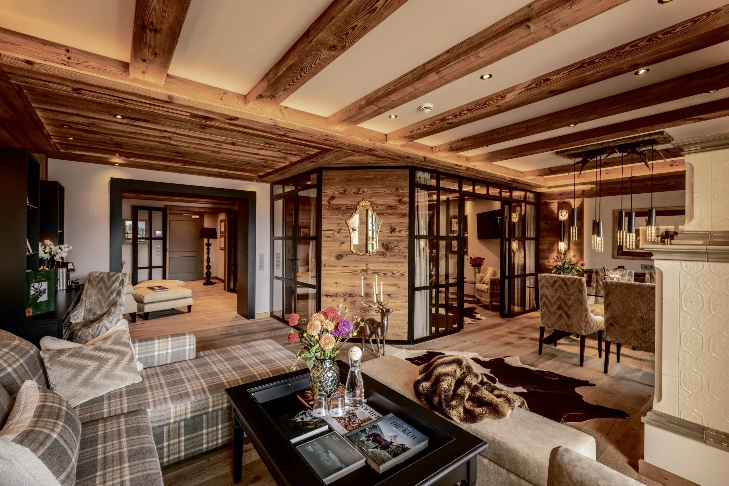Blick in die ger&auml;umige Signature Suite des Alpin Resort Sacher Seefeld &ndash; Tirol mit gem&uuml;tlicher Einrichtung, Holzdecken und eleganter Sitzecke
