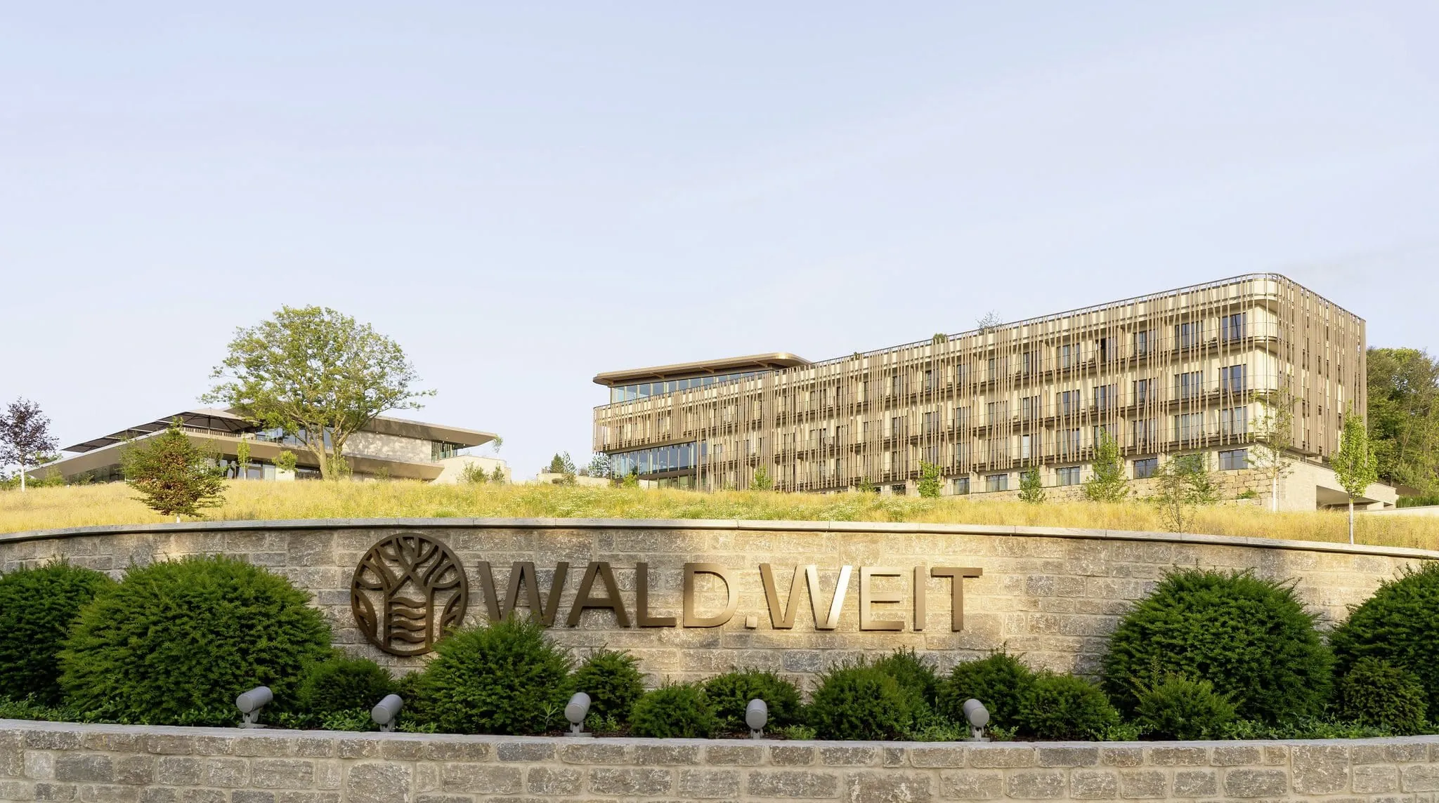 Außenaufnahme des WALD.WEIT Rheingau Hotel & Retreat mit Außenmauer mit Hotelnamen