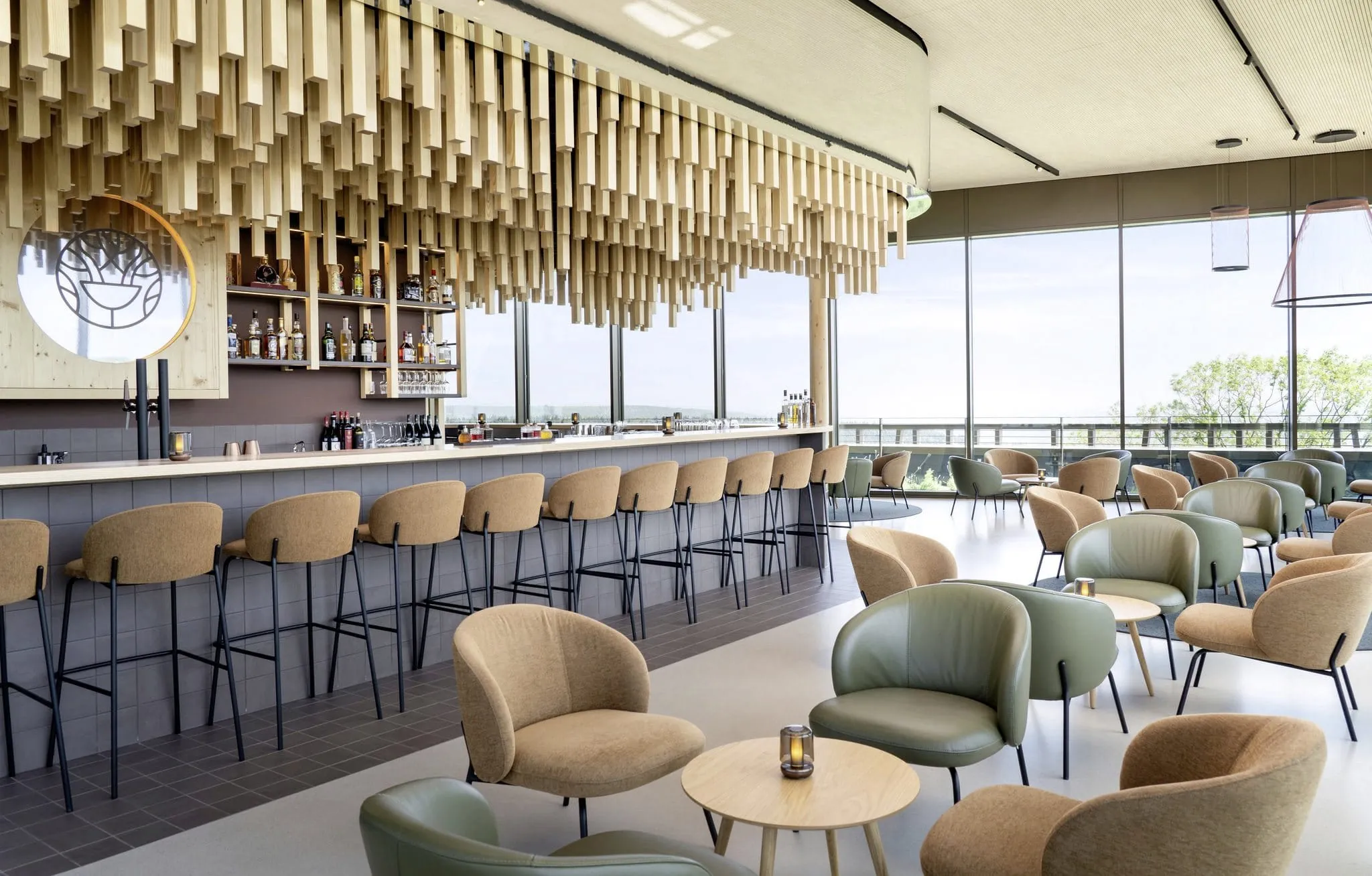 Stylische Hotelbar im WALD.WEIT Rheingau Hotel & Retreat mit Holzstrelen über der Theke und großem Panoramafenster