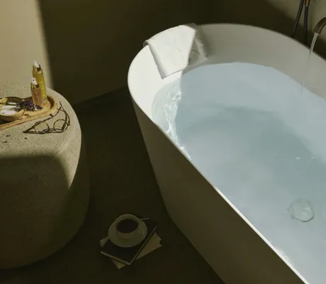 Wasser läuft in weiße Badewanne im Cape of Senses und Kaffeetasse steht daneben