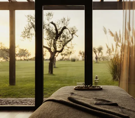 Massageliege mit grauem Frottebezug und Blick in den Garten mit den Bäumen im Cape of Senses