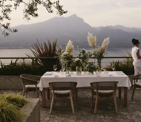 Paar steht auf Terrasse des Cape of Senses mit langem eingedecktem Tisch und mehreren Blumenvasen