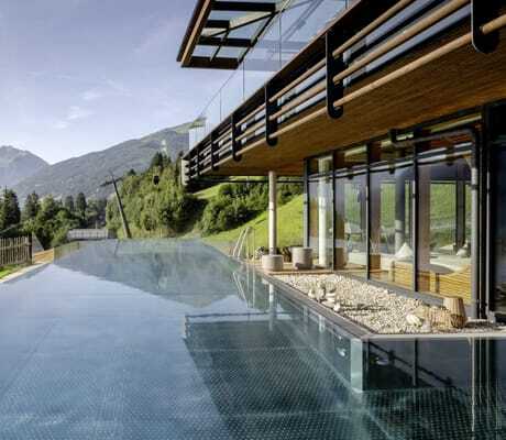 Outdoorpool des DAS.GOLDBERG mit Blick auf die Berge und eine Seilbahn