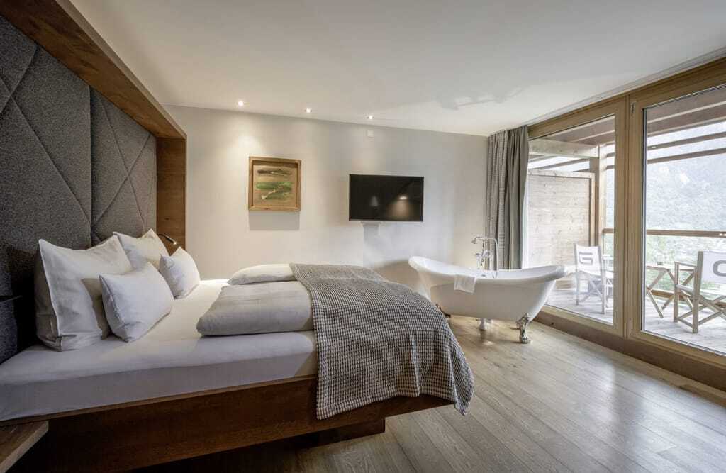 Modernes Hotelzimmer mit Doppelbett, freistehender Badewanne und Balkon mit Bergblick im DAS.GOLDBERG