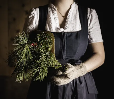 Frau im Dirndl trägt Tannenzweig im Wellnesshotel Der Engel
