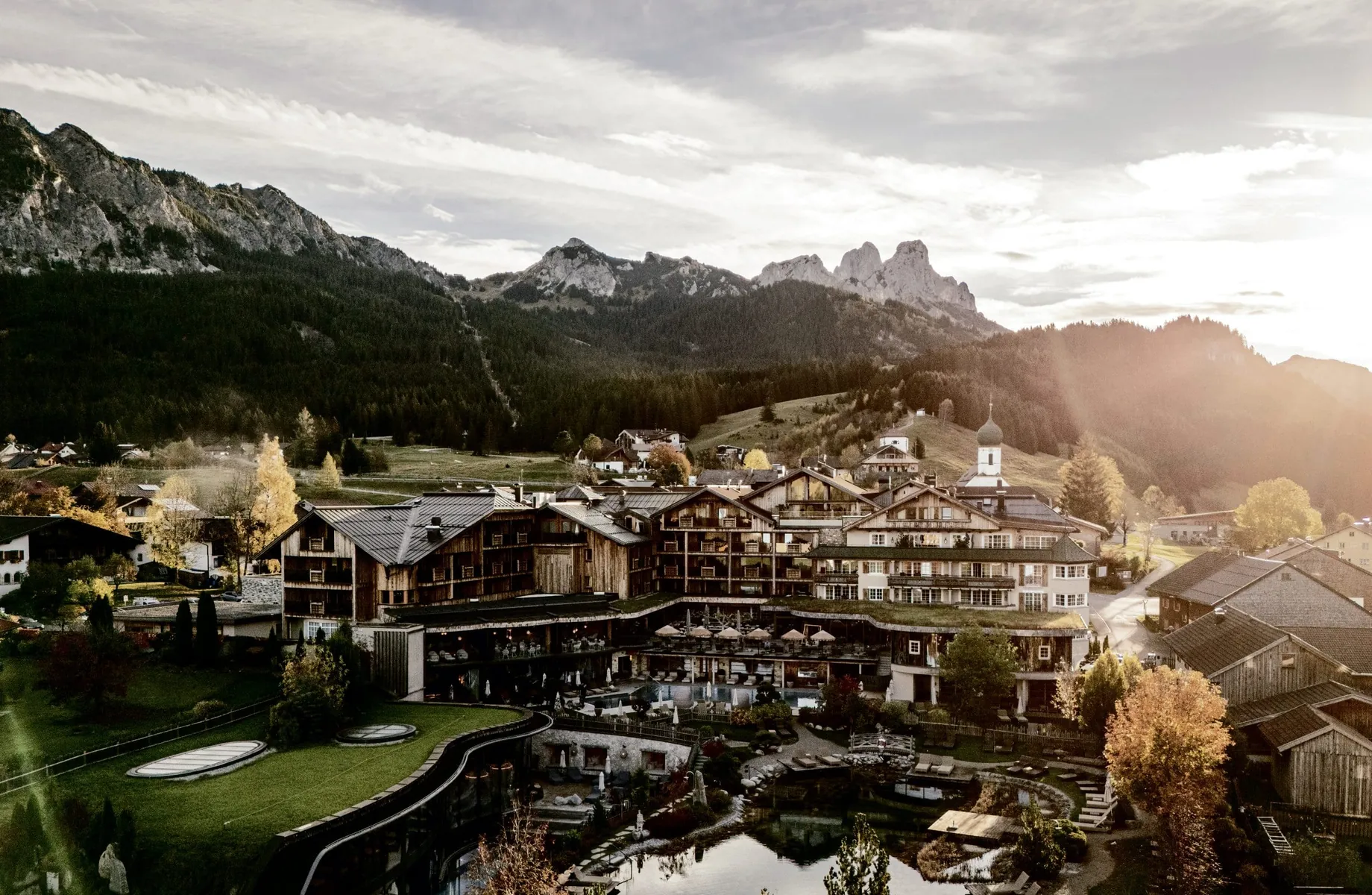 Gesamtansicht des Wellnesshotel Der Engel mit Naturteich und Blick auf die Berge im Hintergrund