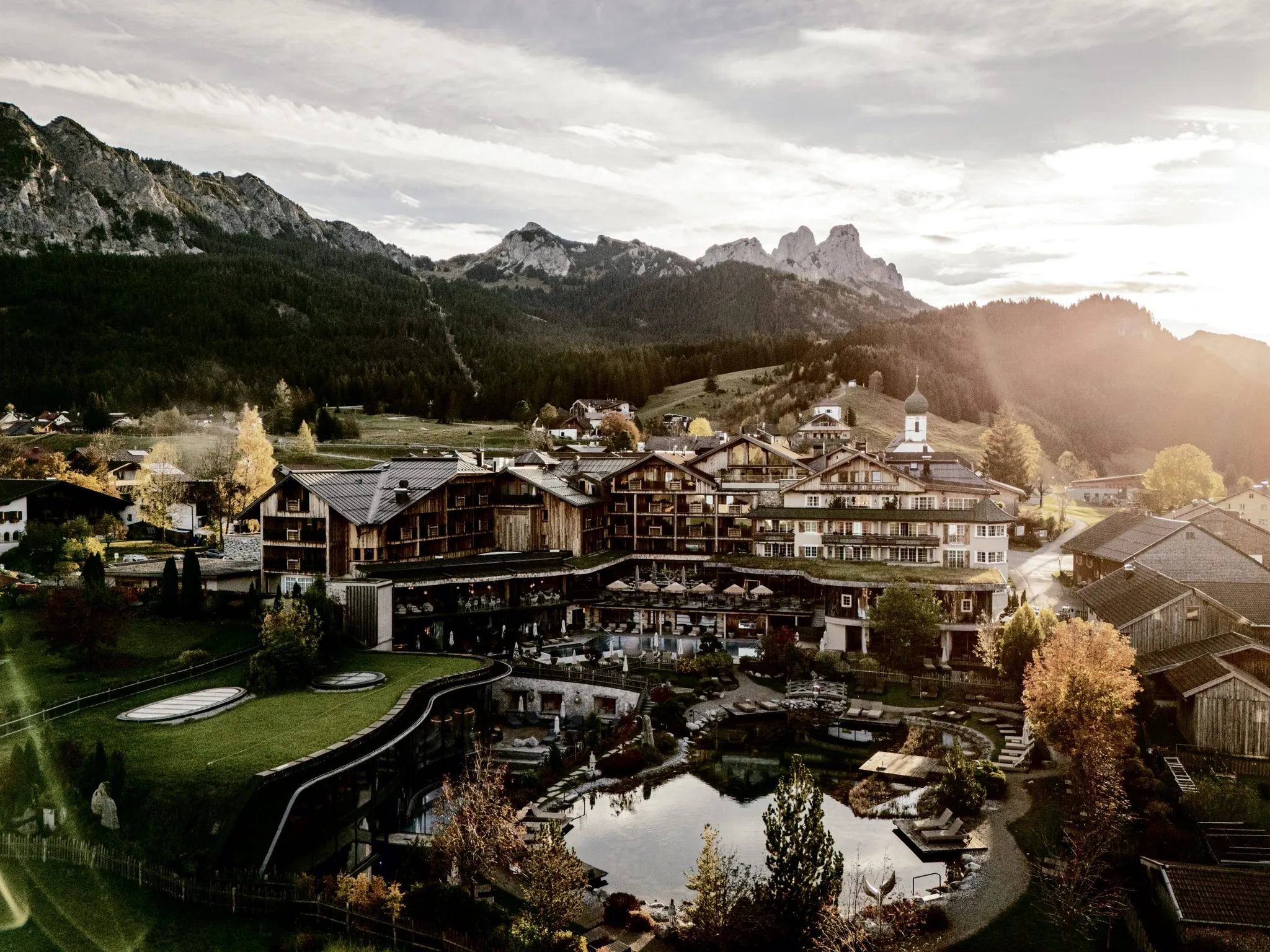 Gesamtansicht des Wellnesshotel Der Engel mit Naturteich und Blick auf die Berge im Hintergrund
