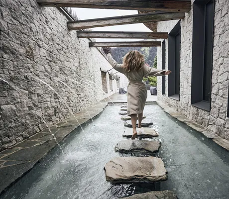 Frau läuft im Kneippbecken des Wellnesshotel Der Engel über die Steine