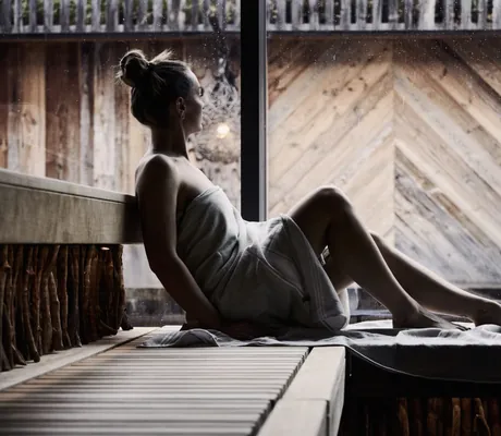 Frau mit Dutt sitzt in der Sauna des Wellnesshotel Der Engel am Fenster