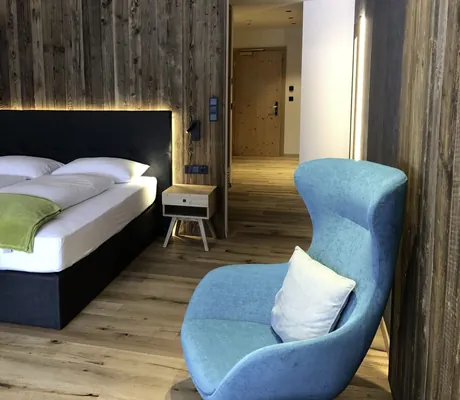 Die Glacier Suite im My Paradies in Sulden, eingerichtet mit dunklem Holz und Samtsessel.