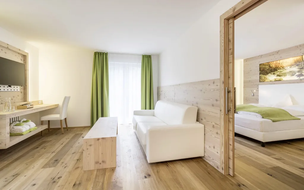 Blick in ein Zimmer im Hotel My Paradies in Sulden, ausgestattet mit hellem Holzmobilar.