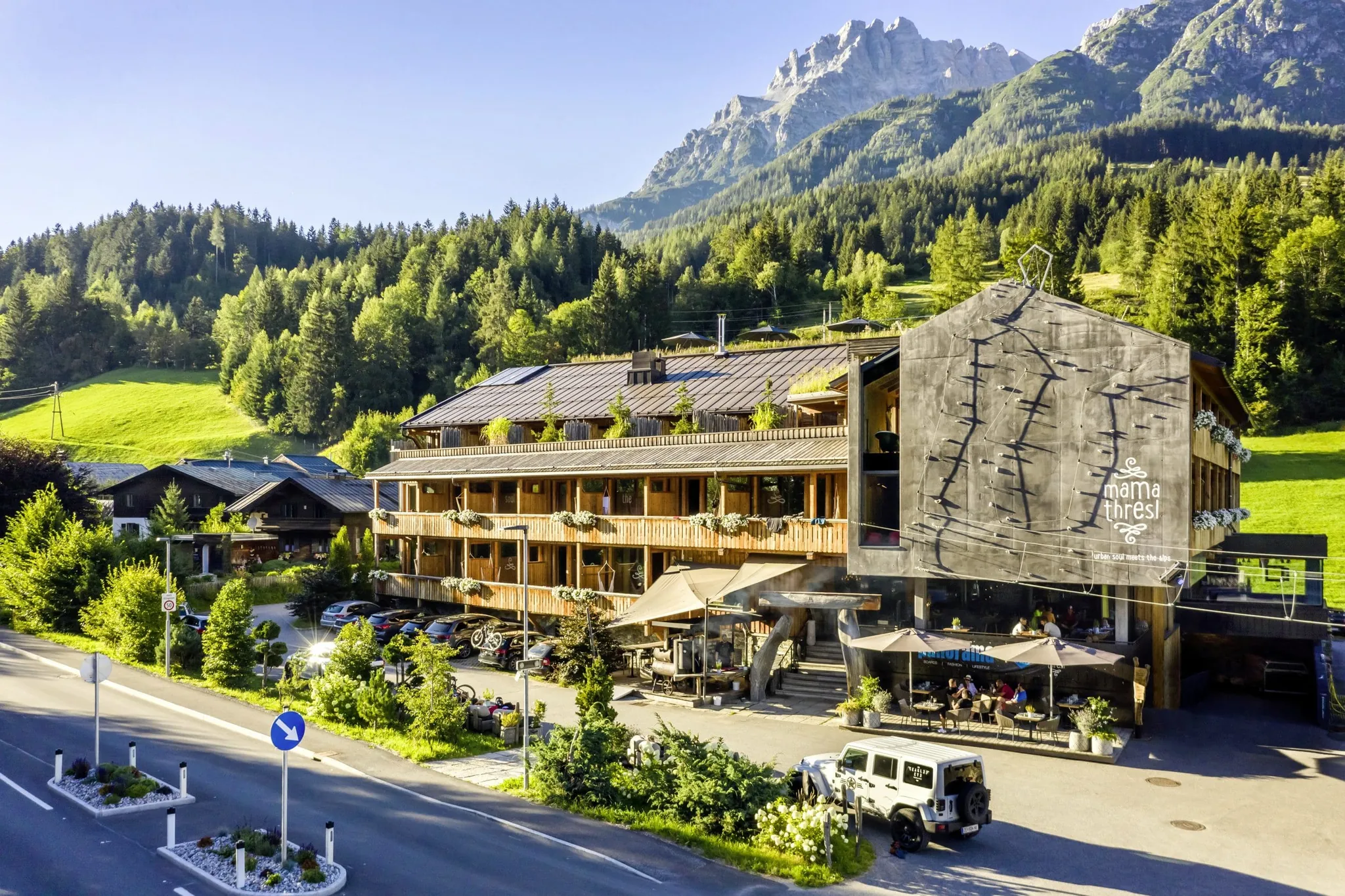 Außenansicht des mama thresl umgeben von Bergen und Wald im Sommer