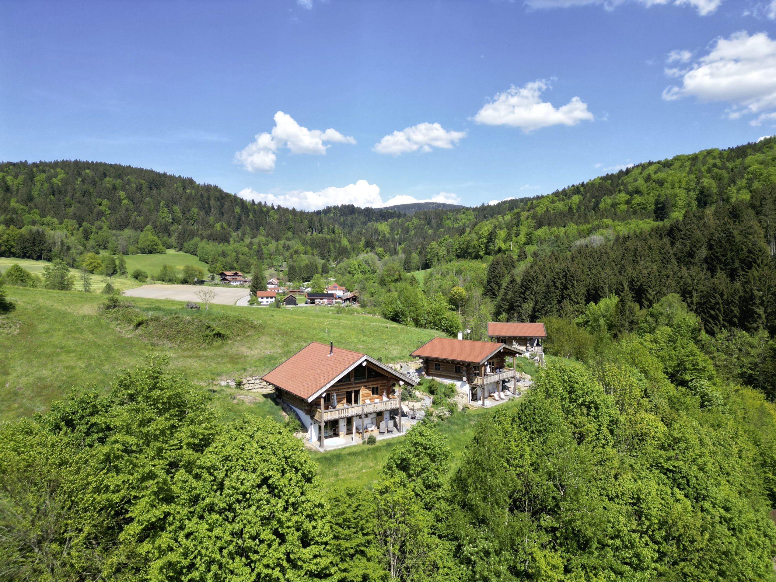 Blick auf die drei Jakob Chalets im Sommer, umgeben von sattgrünen Wiesen und Wäldern