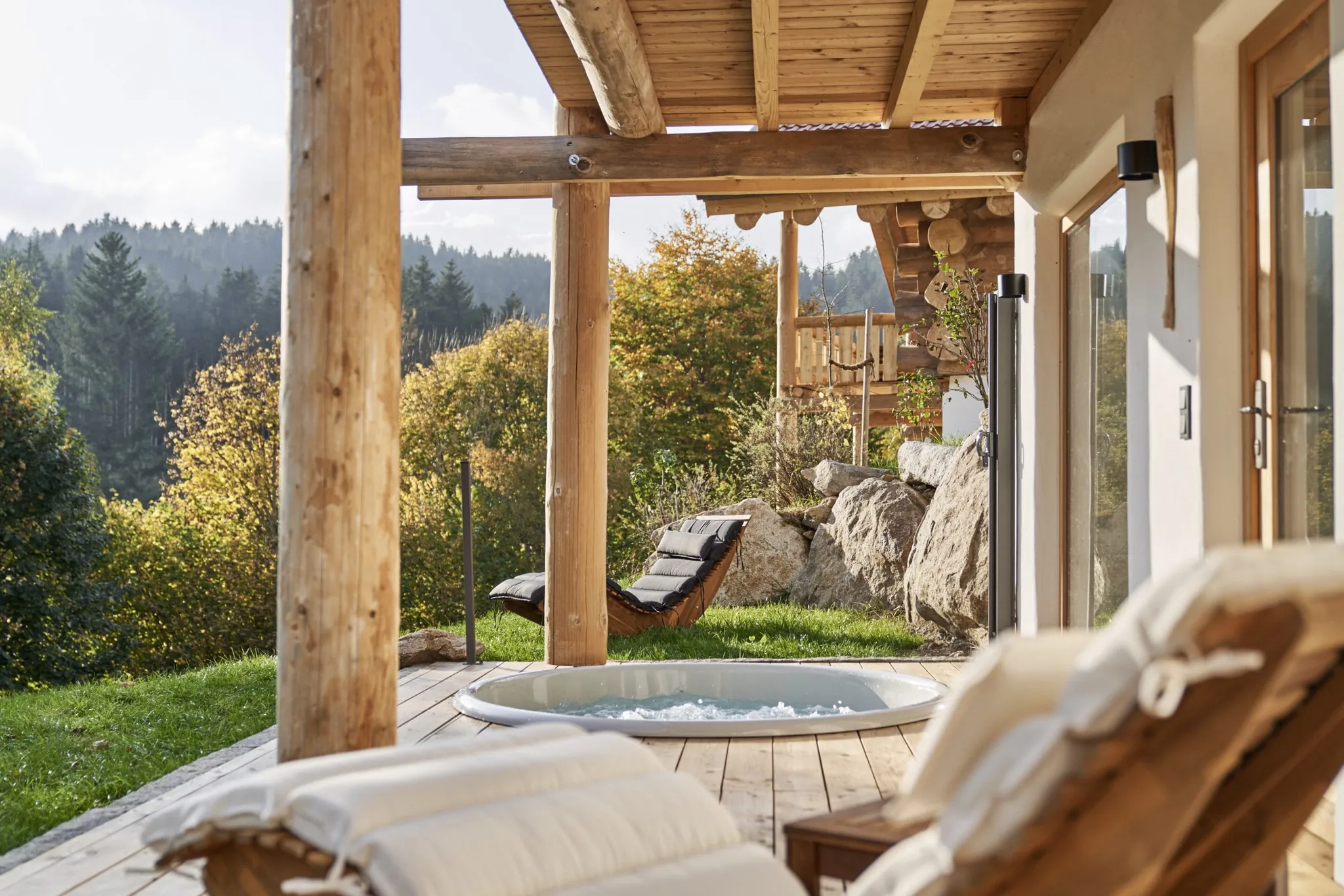 Terrasse der Jakob Chalets mit geschwungenen Wellnessliegen aus Holz und Whirlpool