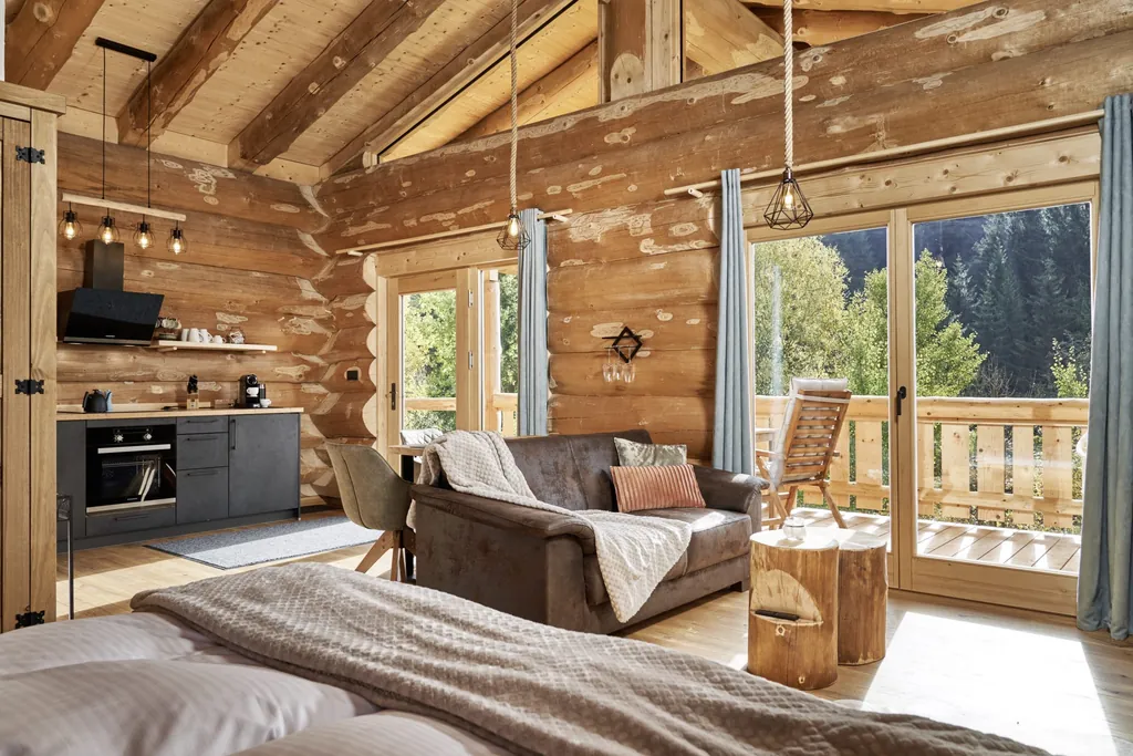 heller Wohn-/Essbereich in einem der Jakob Chalets im Blockhausstil mit Sofa und Küchenzeile im Hintergrund