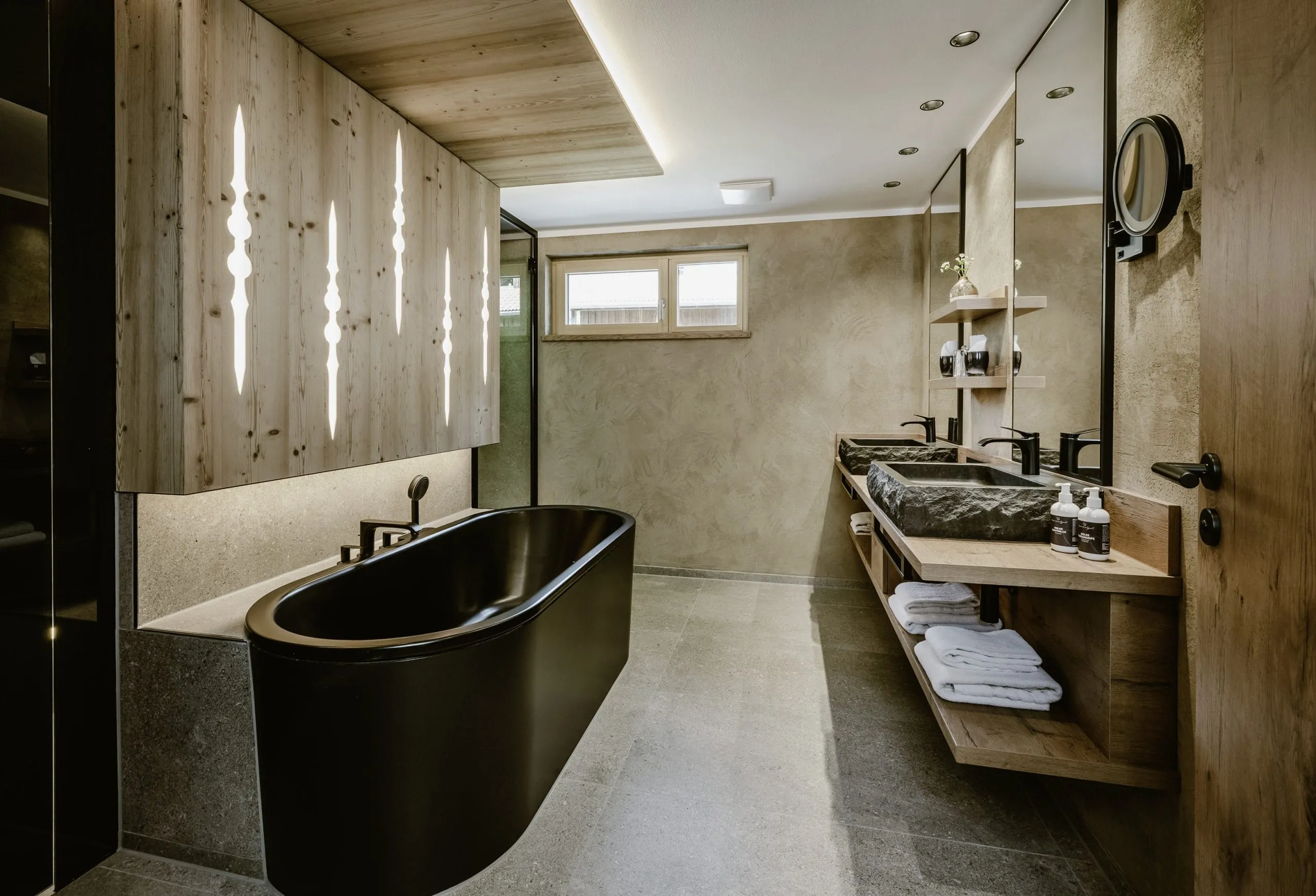 Badezimmer mit schwarzer Badewanne im Bergkristall in Oberstaufen im Allgäu mit viel Holzelementen.