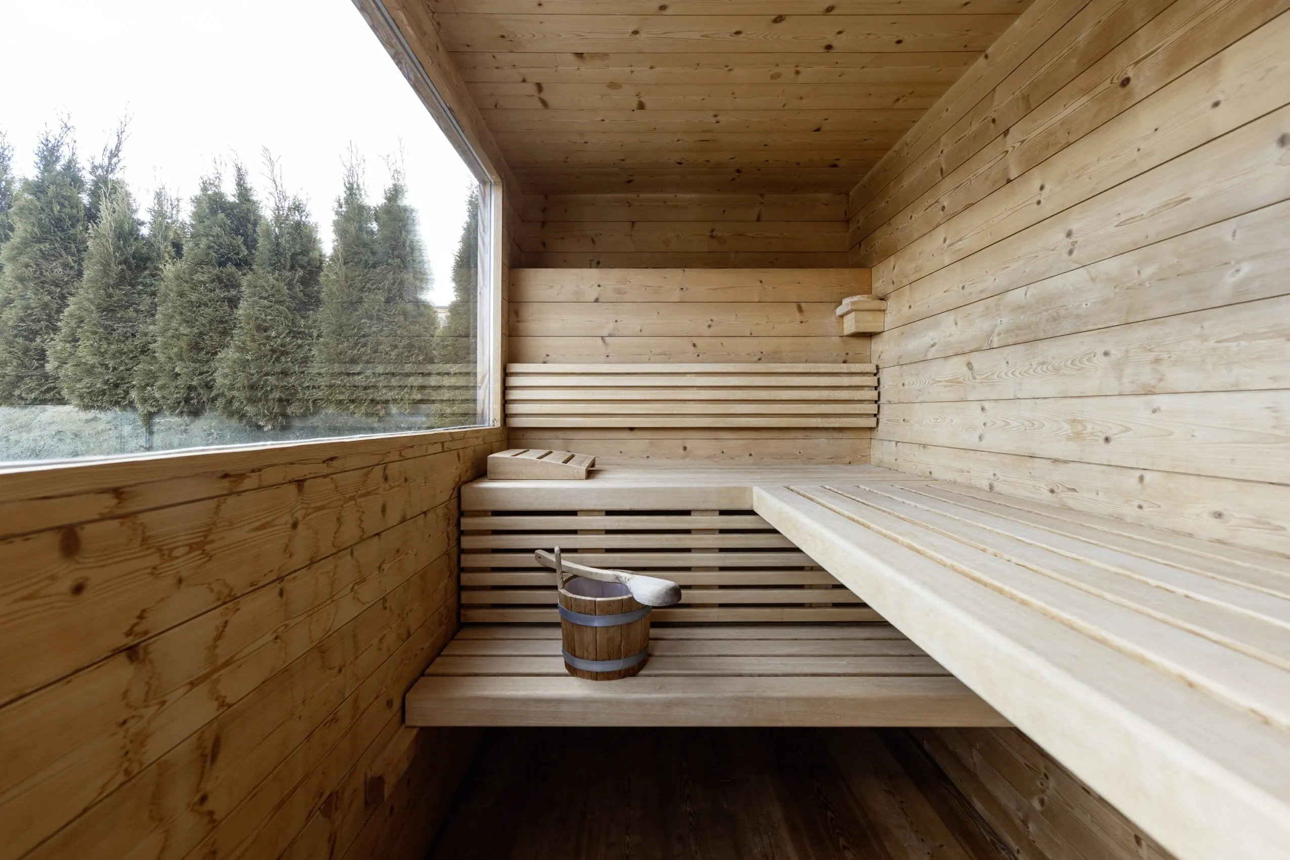 Die private Sauna des GERSTL Alpine Retreat mit Aufgusseimer und Blick in die Natur.