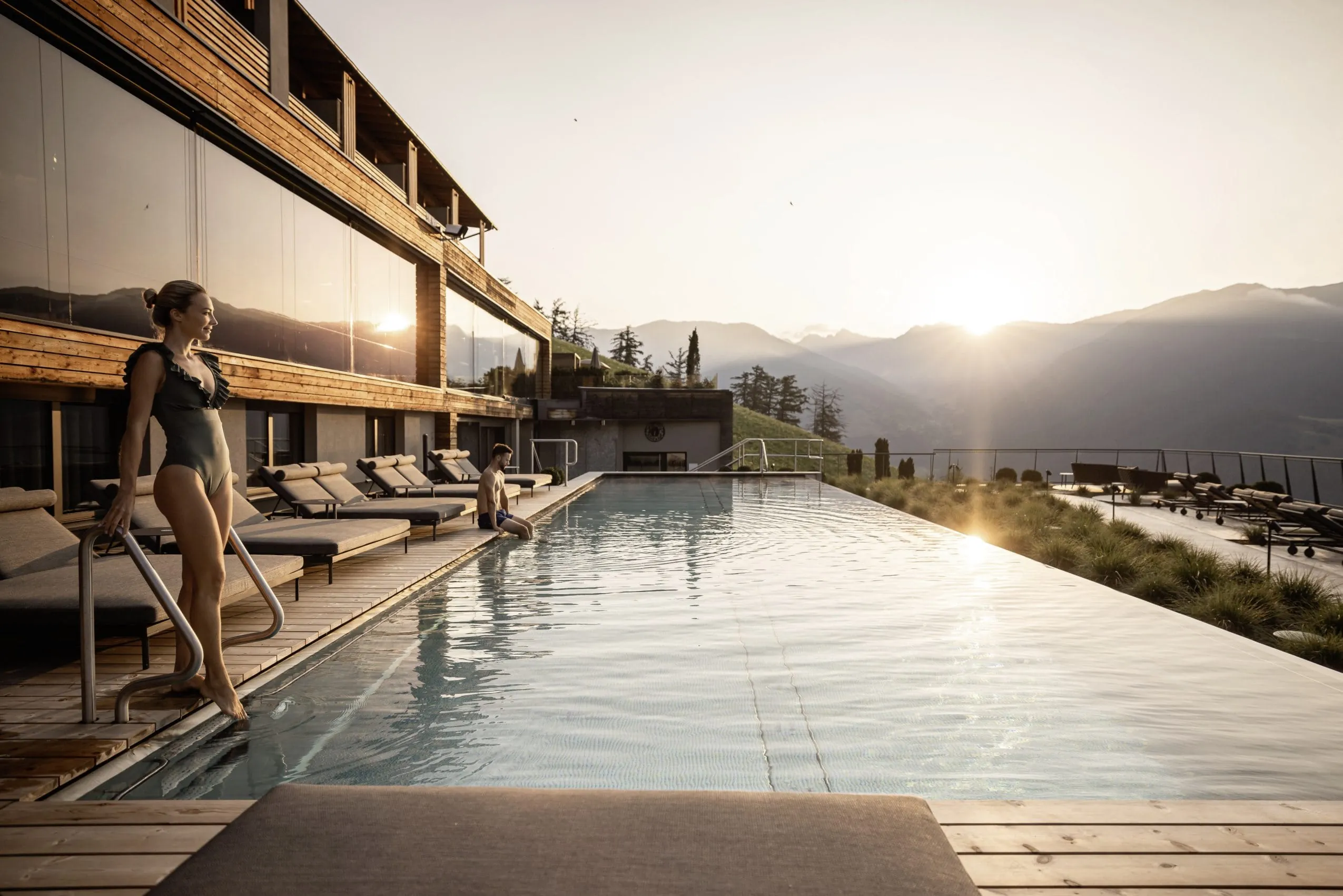 Infinity-Pool mit einem Paar und Blick auf den Sonnenuntergang hinter Bergen im DAS GERSTL in Mals.