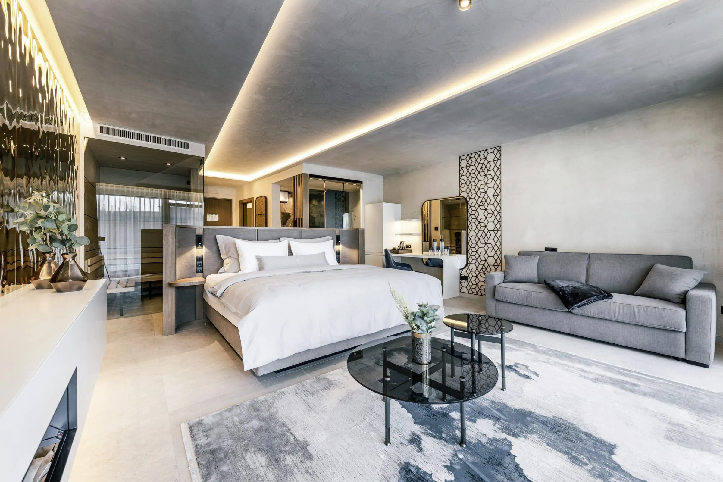 Zimmerblick mit Doppelbett, Sofa und moderner Einrichtung im Quellenhof See Lodge.