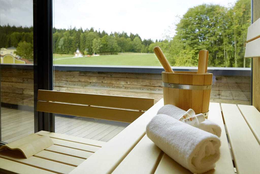 Sauna mit Handtüchern und Aufgusseimer mit Panoramablick auf grüne Wiesen und Bäume im Wellness & Naturresort Reischlhof **** Superior.