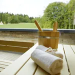Sauna mit Handtüchern und Aufgusseimer mit Panoramablick auf grüne Wiesen und Bäume im Wellness & Naturresort Reischlhof **** Superior.