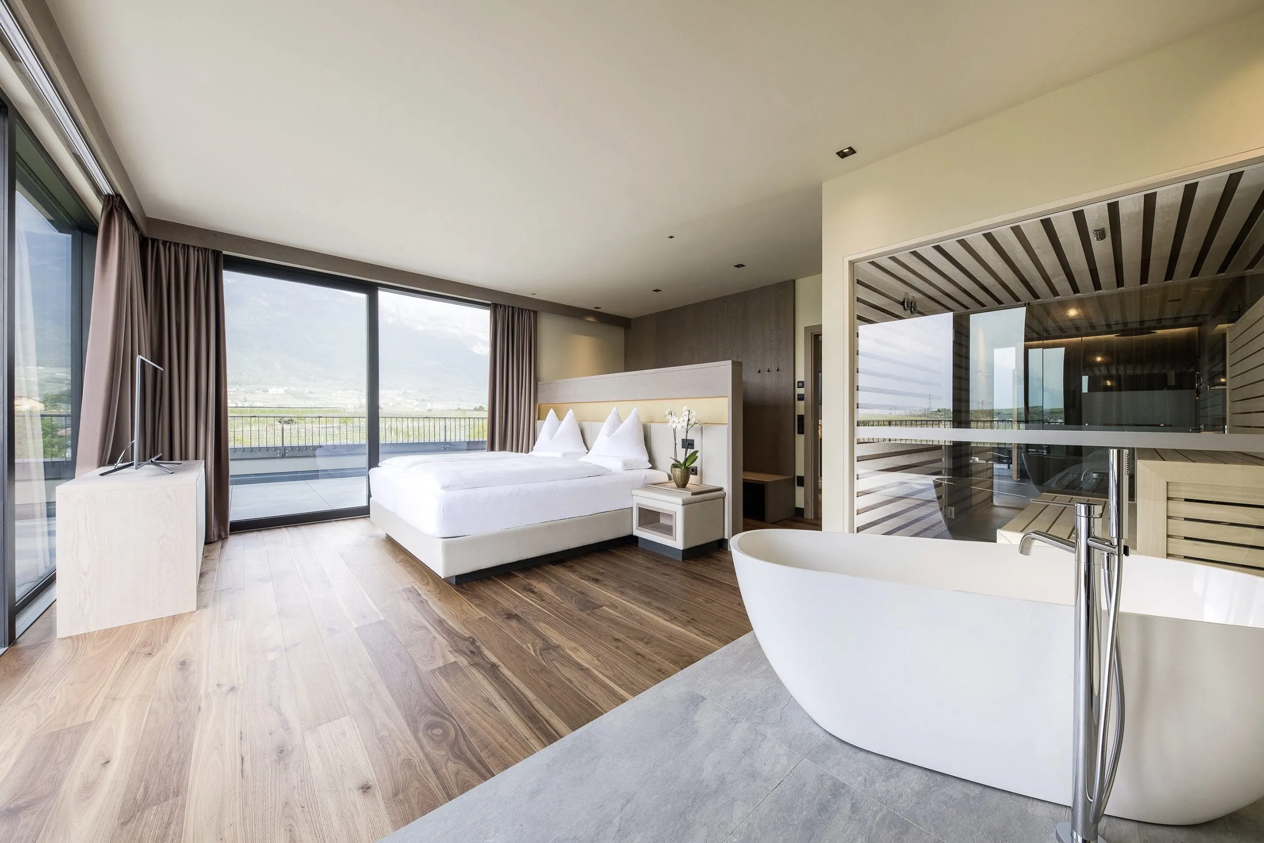 Blick in die Suite im Weinegg Wellviva Resort mit freistehender Badewanne und Sauna sowie Doppelbett.