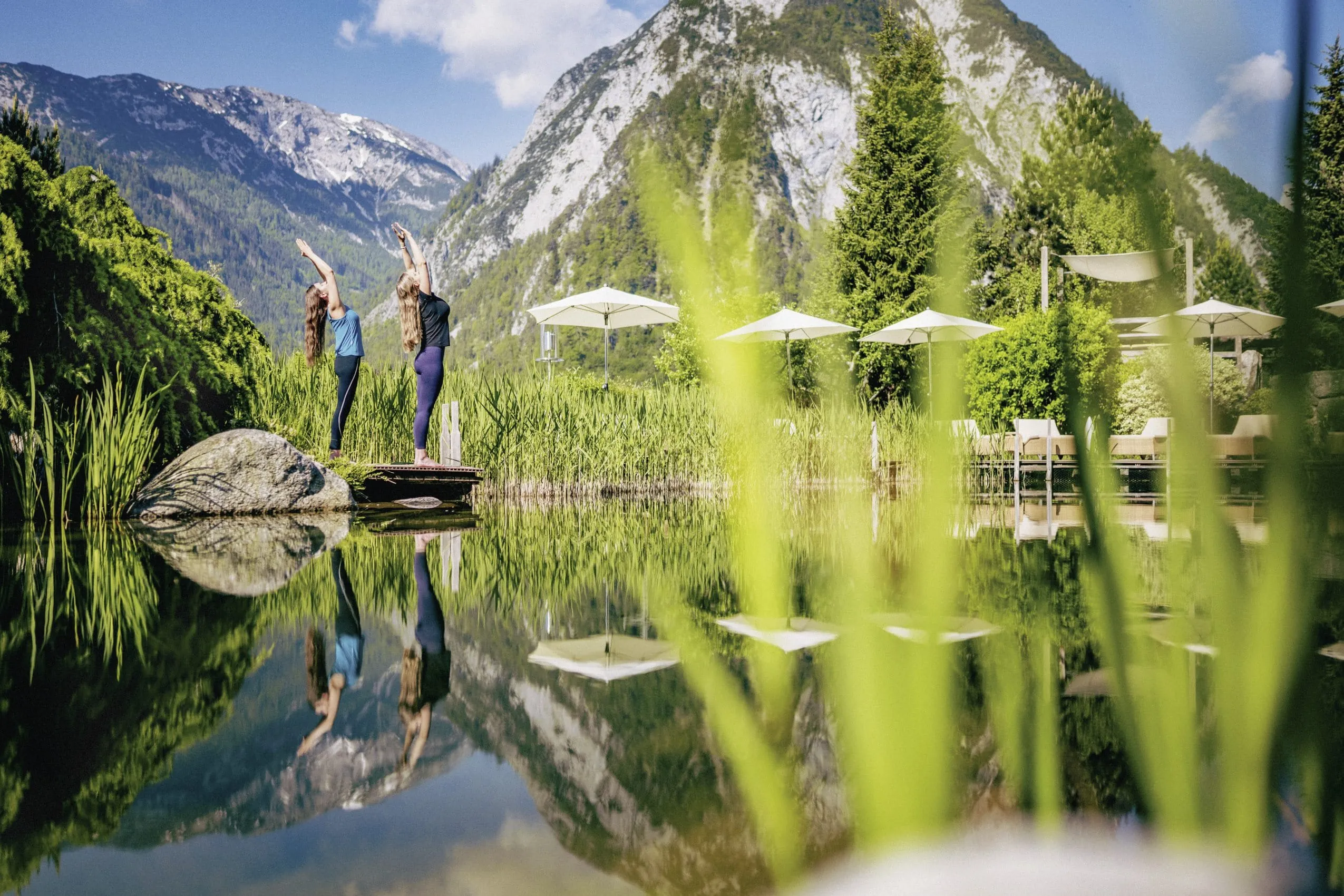 Zwei Frauen performen Yoga in der Wellnessresidenz Alpenrose &ndash; der Alpine Kraftplatz in gr&uuml;ner Umgebung.