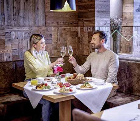 Ein Pärchen stößt im Hotel Brunner Hof in Arnschwang mit einem Gläschen Sekt an einem gedeckten Frühstückstisch an.